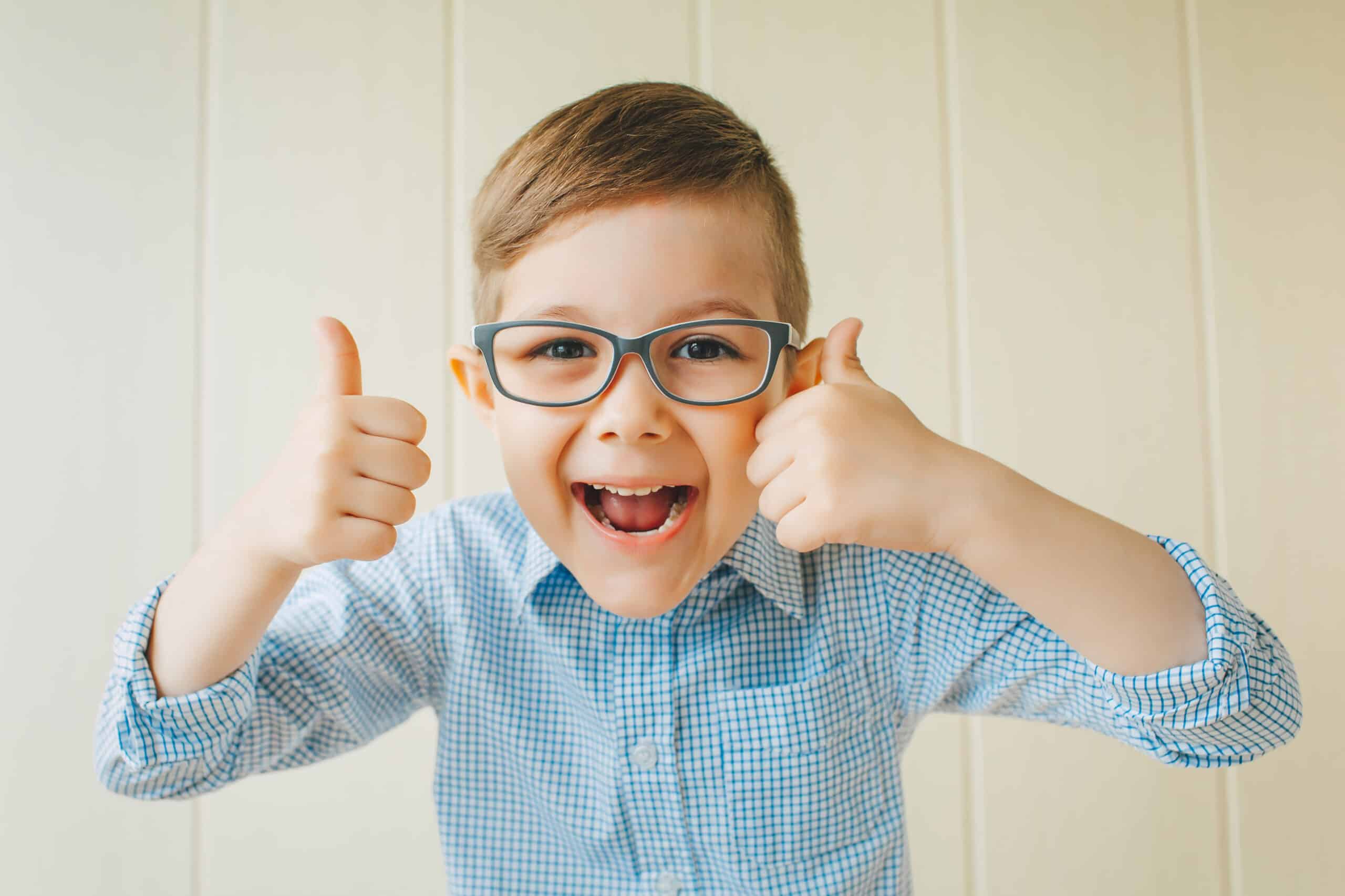A child with glasses gives a thumbs-up. A kid likes the glasses. AdobeStock 163903923 scaled