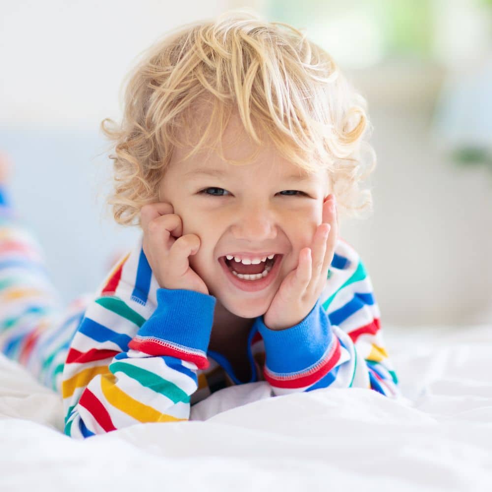 boy laying down laughing with straight and healthy teeth