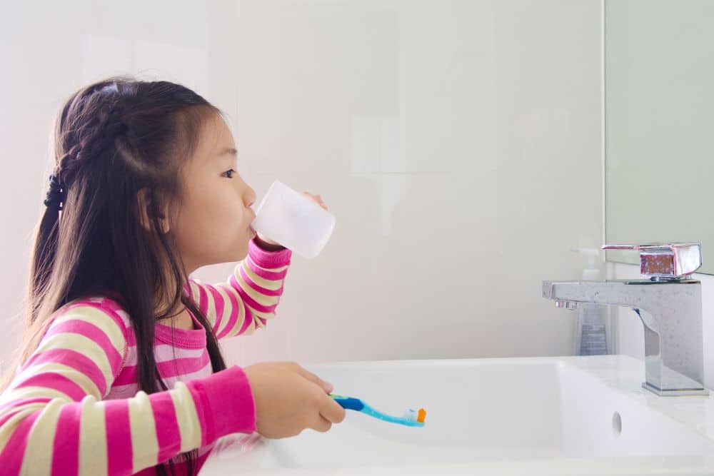 young-girl-rinsing-mouth-brushing-teeth girl in bathroom brushing teeth and rinsing mouth